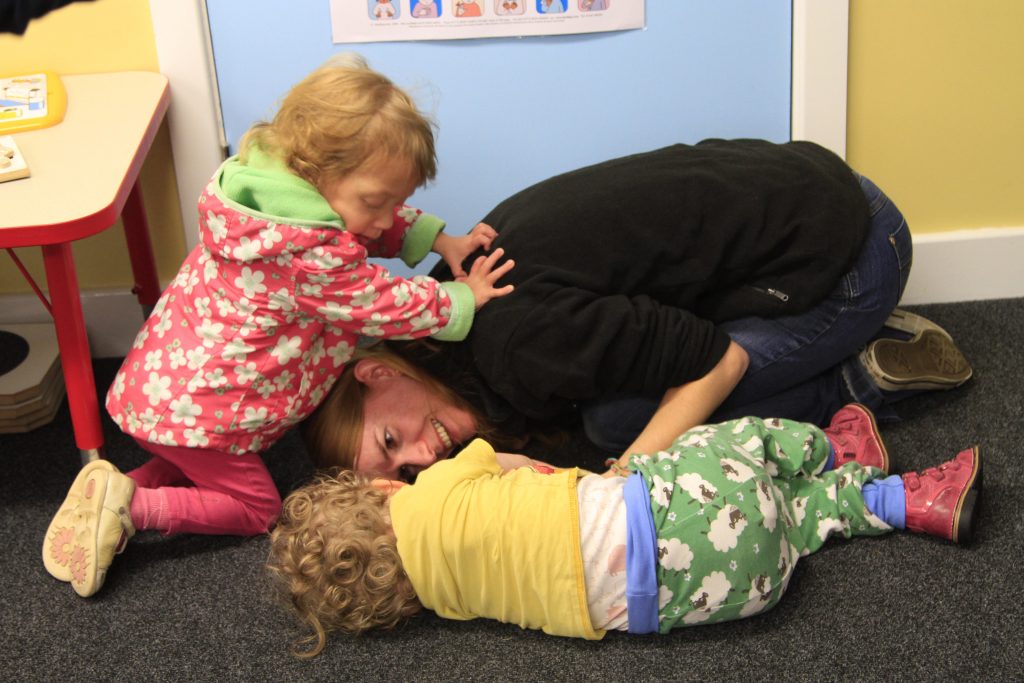 Nursery worker on floor with two small children