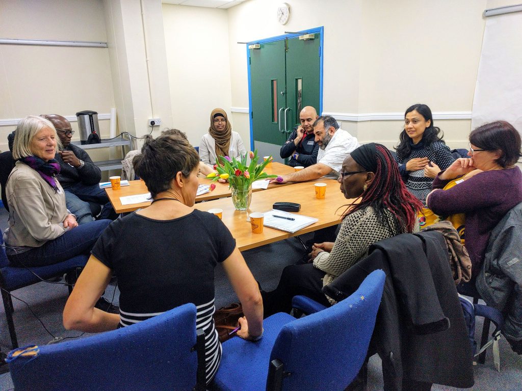 Ten people round a table talking in a workshop