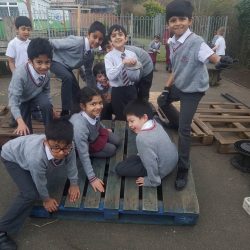 a group of children in uniform playing on a seesaw made of pallets