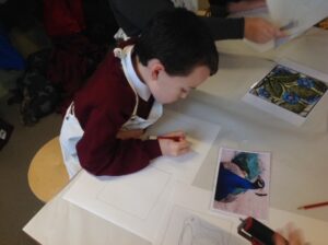 Pyrcroft School visit: medium close-up image of a pupil drawing a picture of a peacock