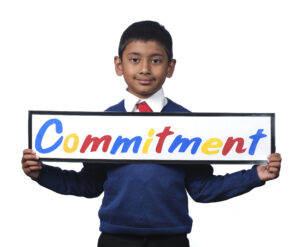 Monega Primary School 4, pupil holding a sign with the text 'Commitment'. Copyright: Monega Primary School