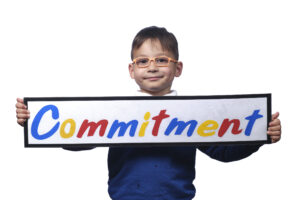 Monega Primary School 1, pupil holding a sign with the text 'Commitment'. Copyright: Monega Primary School
