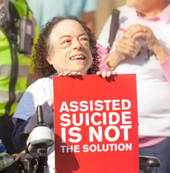Liz Carr holding a red sign that says "Assisted suicide is not the solution"